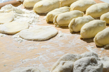 Dough on a Board with flour and pies. Cooking homemade hotcakes with onion and egg filling.