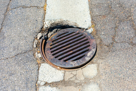 Round Storm Drain Grate Over Damaged Manhole On The Road