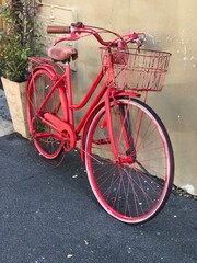 Vintage red bicycle and basket leaning against a concrete wall