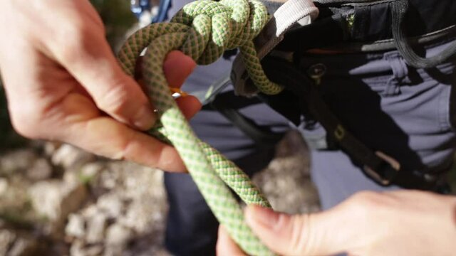The climber is tying a knot on the safety system, Knot made of climbing rope, Safety in extreme sports, Climbing equipment for belaying, The girl is preparing to climb the route.