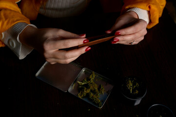 Fototapeta na wymiar Young woman with cigarrette smoking weed hands nails marijuana grinder 