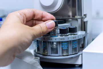 Laboratory concept; close up picture of the scientist put the vial of GC sample on autosampler plate