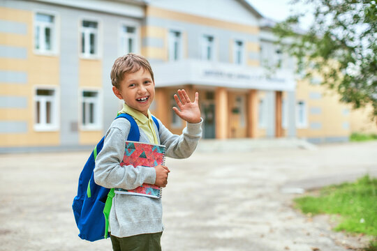 Back To School. A Boy From An Elementary School In The School Yard Waves