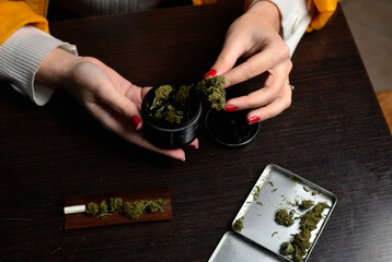 Young woman with cigarrette smoking weed hands nails marijuana grinder 