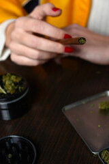 Young woman with cigarrette smoking weed hands nails marijuana grinder 
