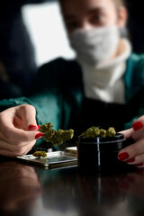 Young woman with face mask smoking weed flame lighter hands nails marijuana grinder 
