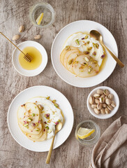 Ricotta with pears, pistachios and honey or maple syrup on two white plate