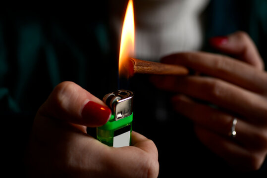 Young woman hands nails fingers burn cigarrette weed lighter flame 