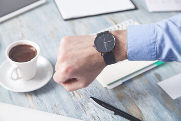 Fototapeta na wymiar Businessman showing wristwatch in office desk.