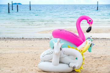 Fancy rubber swim rings on sand beach with blue sea and blue sky background in summer holiday day.