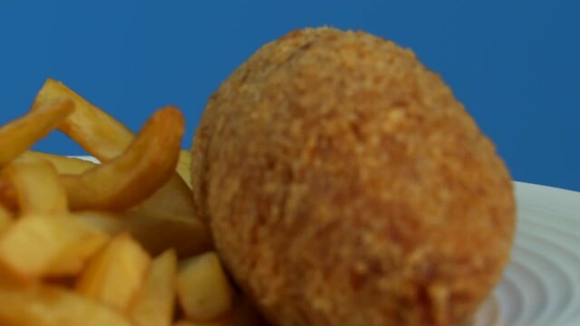 French fries with Kiev cutlet with red sauce spinning on a blue background