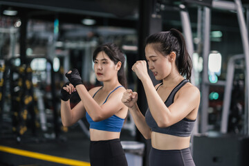 Fototapeta na wymiar Sporty young asian women training boxer wearing strap on wrist with coach