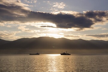 ships at sea against the background of the rays of dawn breaking through the mountains