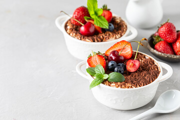A beautiful portioned serving of Italian tiramisu dessert, garnished with strawberries, cherries and mint on a white background. Copy space for your text.