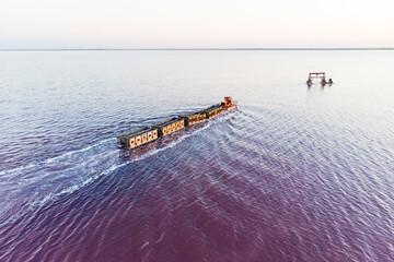 train travels from water. Mined salt in Lake Burlin. Altai. Russia. Bursolith. Old train rides on the railway laid in the water through the salt lake. aerial view, view from the top