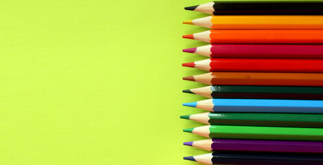 Colored pencils on a yellow background. Lots of different colored pencils. Colored pencil. Pencils are sharp. Pencils are on the left. Close-up. Copy space. Background. Flat lay