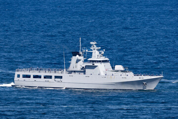 Naval vessel with crew members on the deck as it sails out to sea.