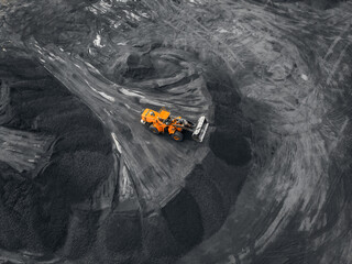 Yellow excavator loads coal into crusher. Open pit mine, extractive industry, top view aerial drone