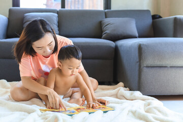 Obraz na płótnie Canvas Asian mom reading book with her son