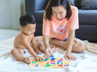 Obraz na płótnie Canvas Asian mom teaching her baby boy. .