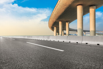 Asphalt road and viaduct with river on a sunny day.