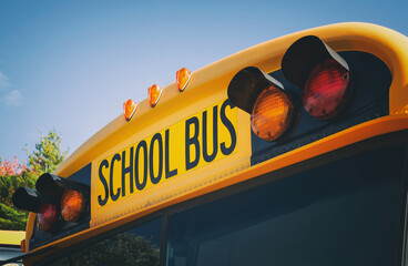 Top of a yellow school bus with lights and text. Closeup against blue sky in the fall. Back to school concept. Copy space. - 367441137