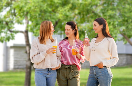 Friendship And Leisure Concept - Group Of Happy Young Women Or Female Friends With Non Alcoholic Drinks Talking Over Summer Garden Background