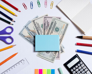 Top view photo of dollars for shopping in the center and colorful stationery, isolated on white with copy space