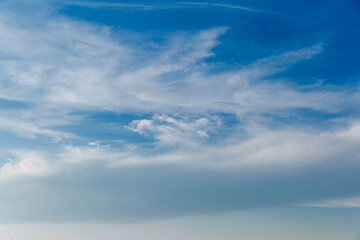 Landscape of stretched clouds of white light against a blue sky