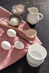 cooking food and culinary concept - eggs, milk, flour, wooden spoon and vanilla on table