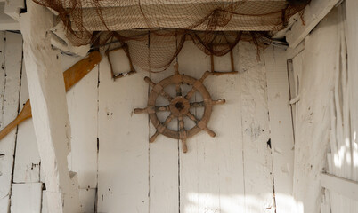 A wooden marine steering wheel hangs on the wall as a decorative element.