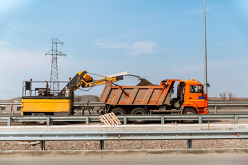 Dismantling of asphalt pavement. Road works. Recycled asphalt crumb is poured over the conveyor belt into the truck body