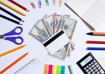 Top view of a photo of dollars and a bank card in the center and colorful stationery, isolated on a white background