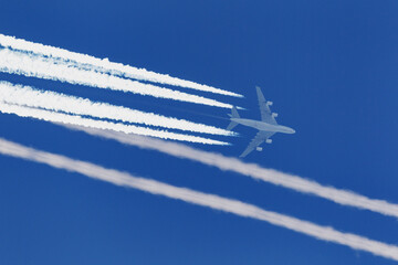 Large four engined commercial airliner jet aircraft flying at high altitude with a large contrail...