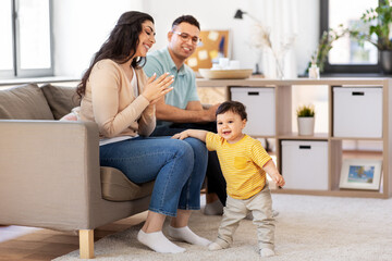 family and people concept - happy mother, father and baby son sitting on sofa at home