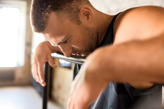 fitness, sport, training and lifestyle concept - close up of tired young man exercising on parallel bars in gym