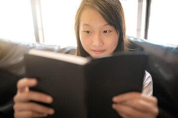 asian teenager girl reading the book/diary near to the window
