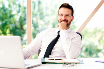 Naklejka premium Cropped shot of businessman looking at camera and smiling while sitting at office desk