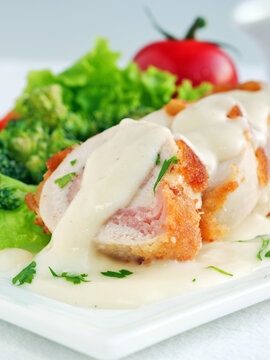 Chicken cordon bleu sliced with parmesan cream sauce and vegetables, vertical