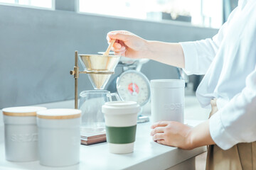 Fototapeta na wymiar 朝の明るい白いキッチンでドリップコーヒーの準備をしている　coffee drip kitchen