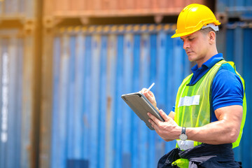 Industrial worker working at cargo freight logistic warehouse wit computer tablet for online assignment. Import and export business.