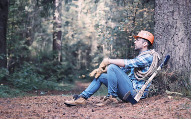 Male lumberjack in the forest. A professional woodcutter inspects trees for felling.