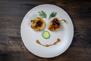 Baked yellow pepper, cucumber, green dill and french old-fashioned dijon mustard on a plate in the shape of a happy face, top view