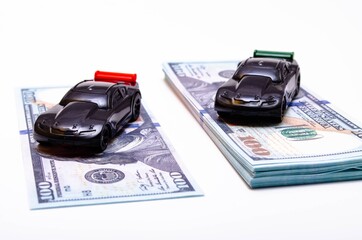 Two sports cars in black on two piles, piles of dollar bills podium. One pile, a pile more, another...