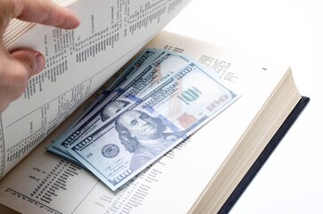 100 dollar bills lie in a black book on a white background in close-up. A man's hand opens a book with dollars. Find, a stock for a rainy day dollars. Inheritance