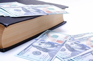 100 dollar bills lie in a black book on a white background in close-up. A man's hand opens a book with dollars. Find, a stock for a rainy day dollars. Inheritance