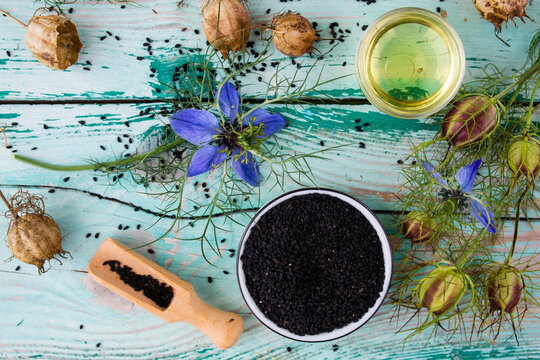 Black cumin flowers and seeds on a wooden background. Healthy diet and alternative medicine.