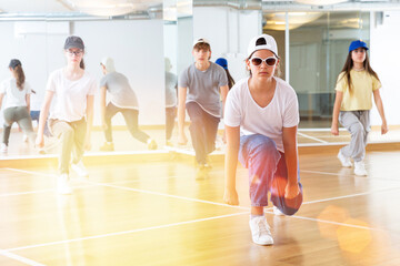 Obraz premium Group of teenagers in casual clothes training hip-hop in class, learning modern dance movements