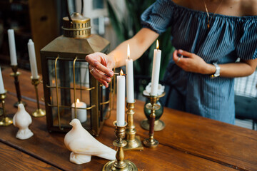 Fototapeta na wymiar female hand lights candles on wooden table. romantic dinner.