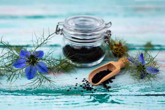 Black cumin flowers and seeds on a wooden background. Healthy diet and alternative medicine.